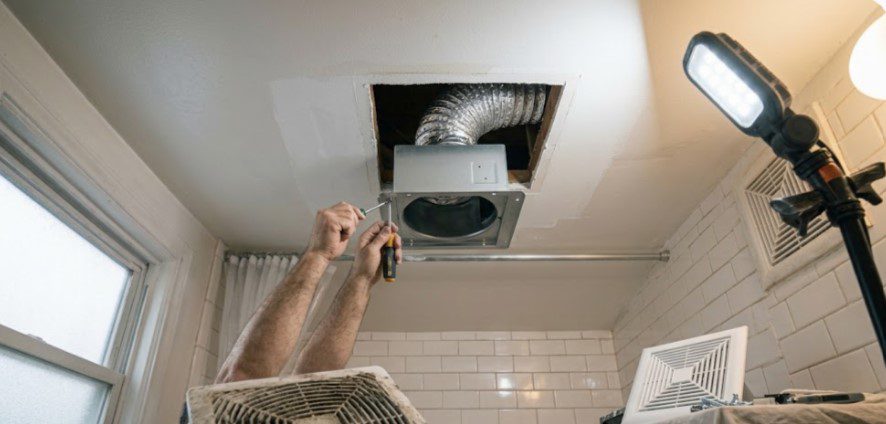 Installing a new bathroom exhaust fan with insulated duct through a repaired ceiling opening, old dirty fan on a table
