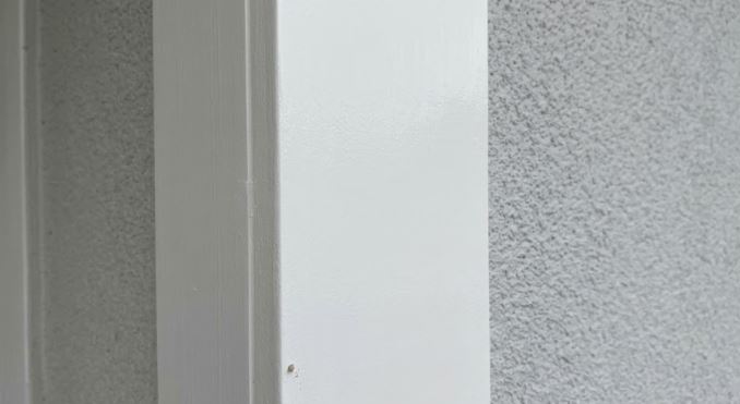 the same white porch column beside stucco on a Potomac, MD home after the streaked area was recoated, dry and even