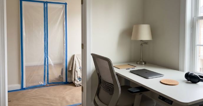 home office desk kept clear while a nearby room is painted