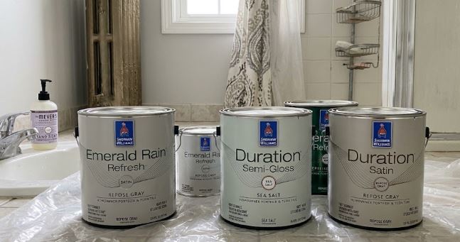 homeowner-supplied Sherwin-Williams paint cans on plastic sheeting in a bathroom before painting