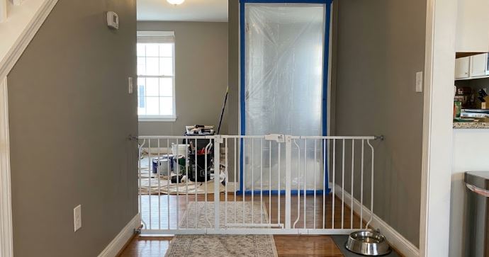 pet gate and taped plastic doorway separating a room being painted