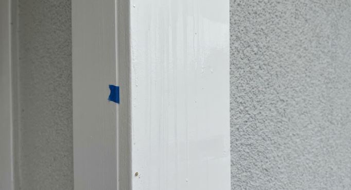 vertical streaks and spotting on a freshly painted white porch column beside stucco on a Potomac, MD home after rain